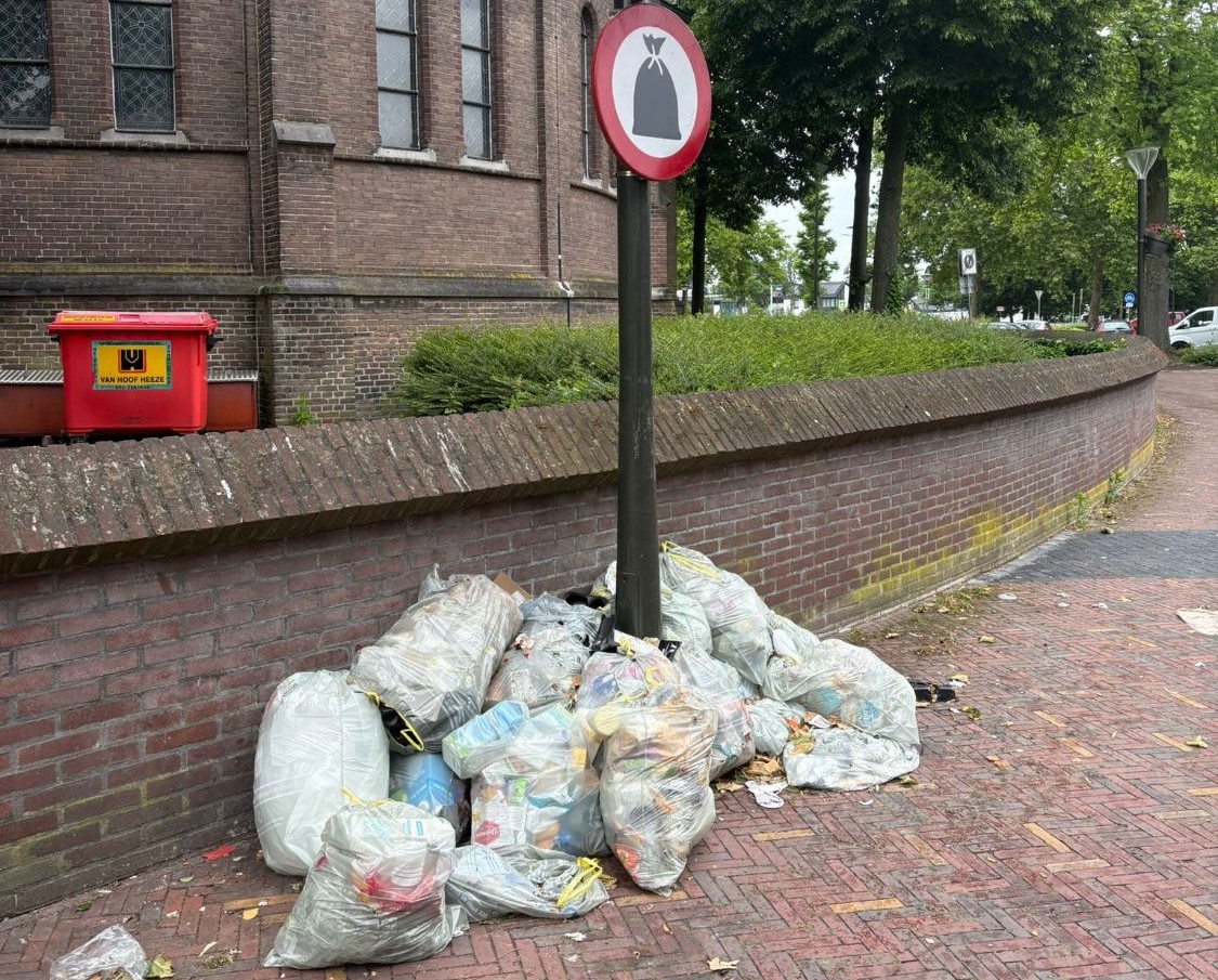 Zakken met plastic, blik en drankenkartons op de stoep onder een verbodsbord voor afvalzakken, afvalstoffenheffing 2027